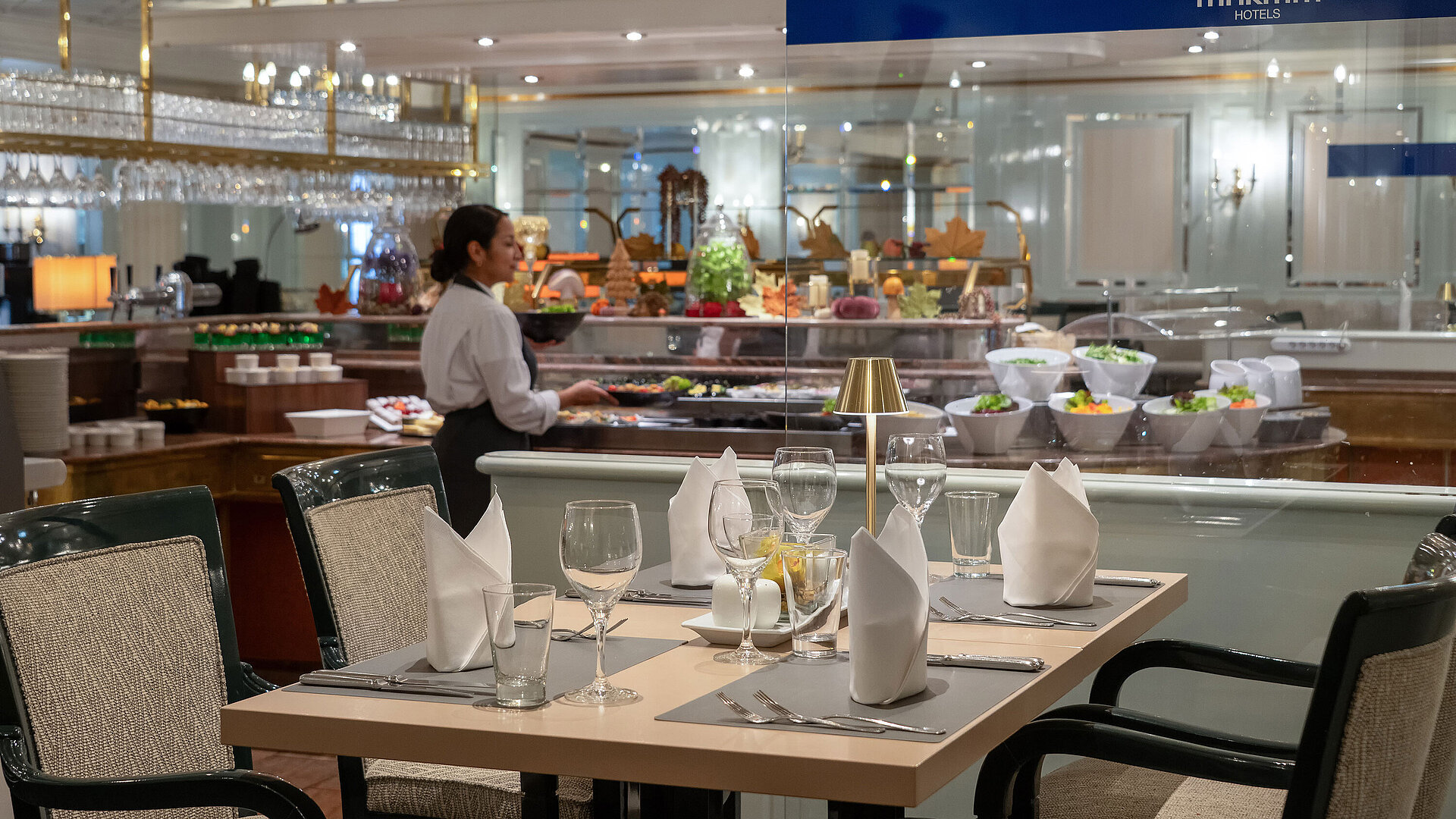 Restaurantbereich mit gedecktem Tisch, Buffetstation im Hintergrund und Servicekraft im Maritim Hotel.