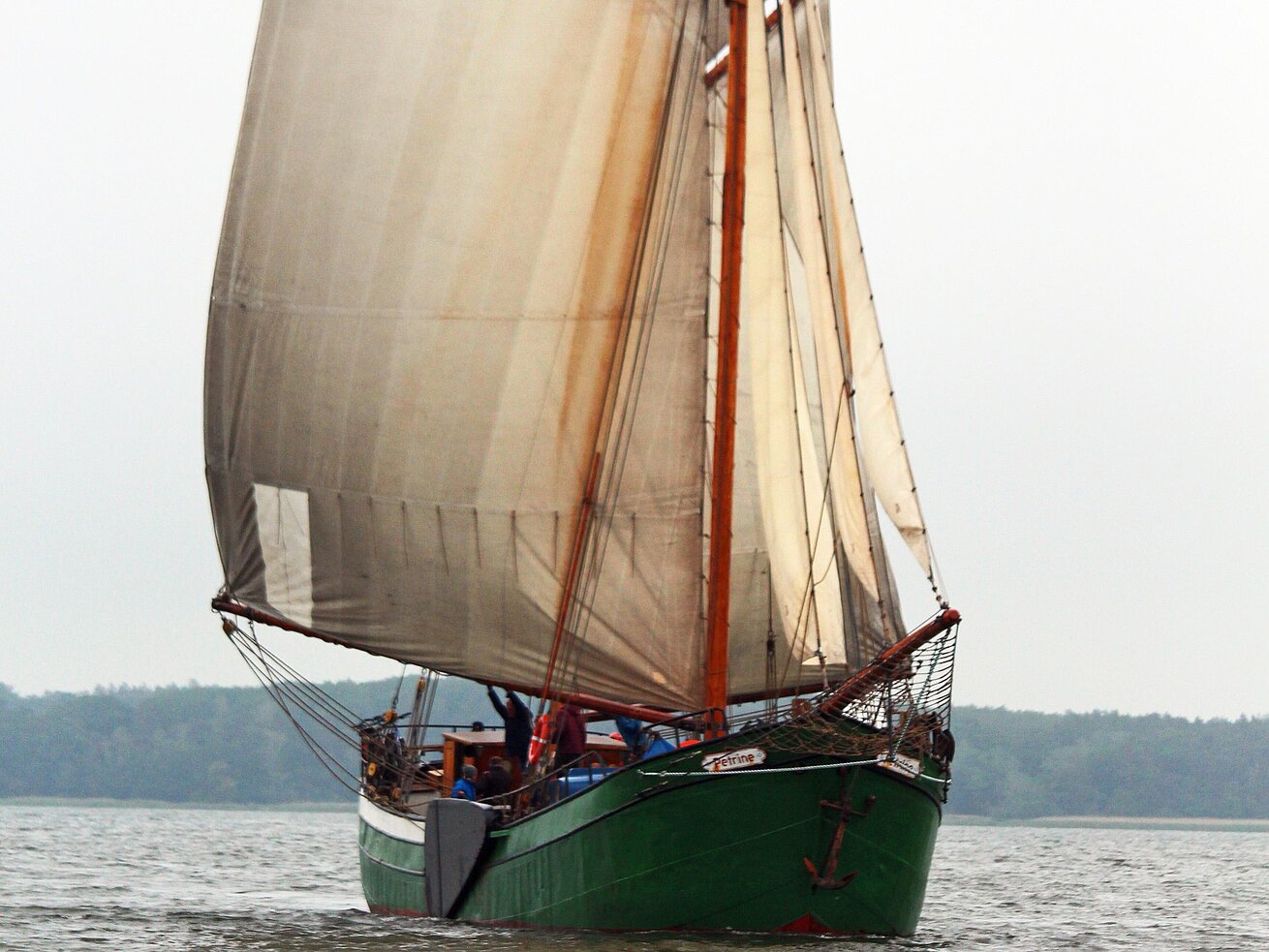 Traditionelles Segelschiff Ein traditionelles Segelschiff mit grünem Rumpf und gesetzten Segeln fährt auf dem Wasser.