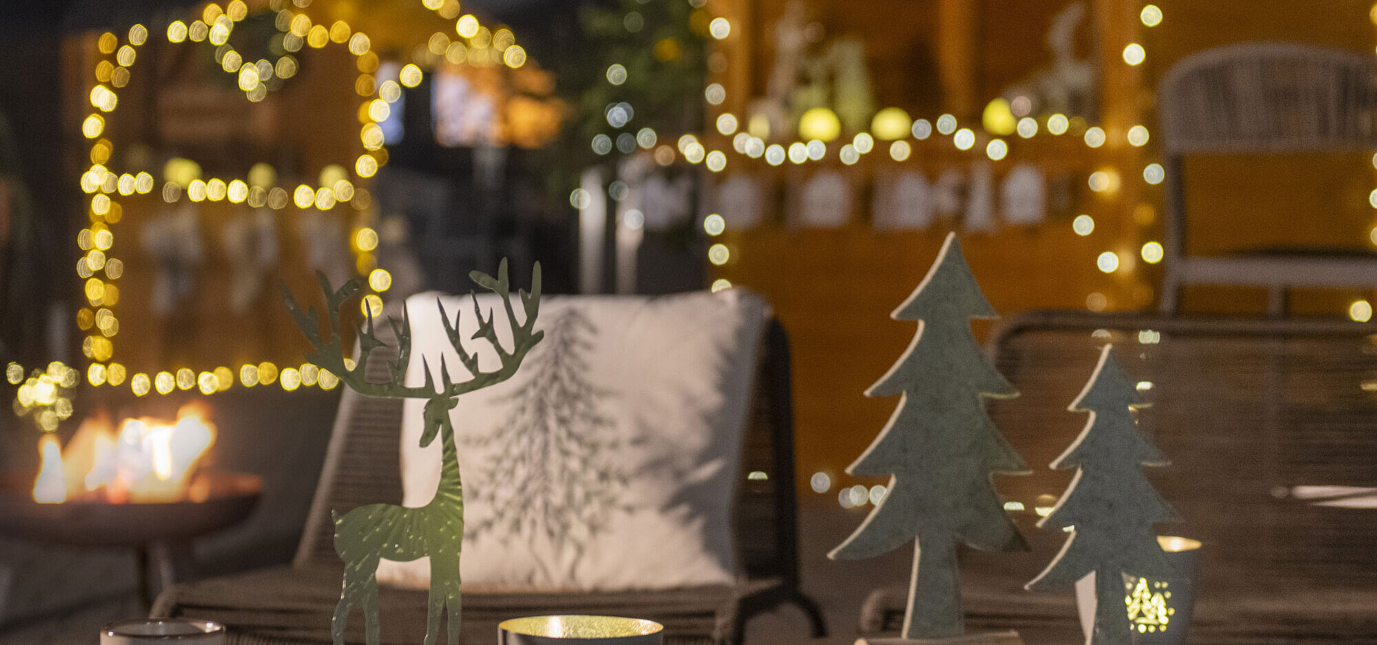 Weihnachtlich geschmückter Außenbereich des Maritim Hotels Darmstadt mit Lichterketten, Holzdekorationen und einem Feuerkorb.