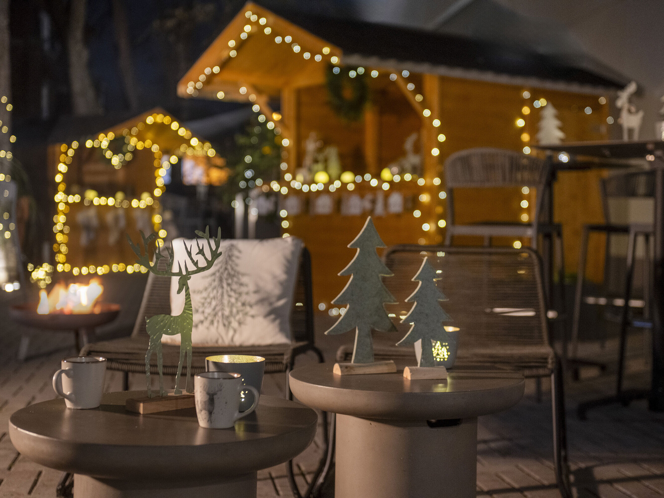 Weihnachtlich geschmückter Außenbereich des Maritim Hotels Darmstadt mit Lichterketten, Holzdekorationen und einem Feuerkorb.