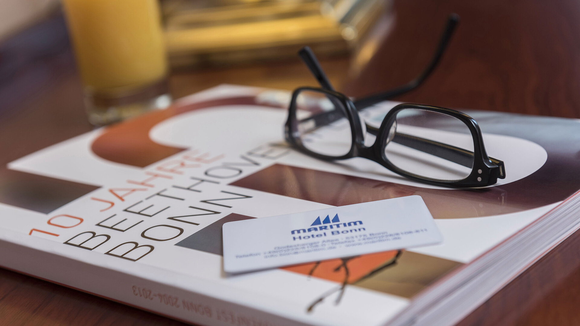 Sehenswürdigkeiten Detailaufnahme aus einem Zimmer im Maritim Hotel Bonn mit Brille, Hotelkarte und einem Buch über Beethoven.