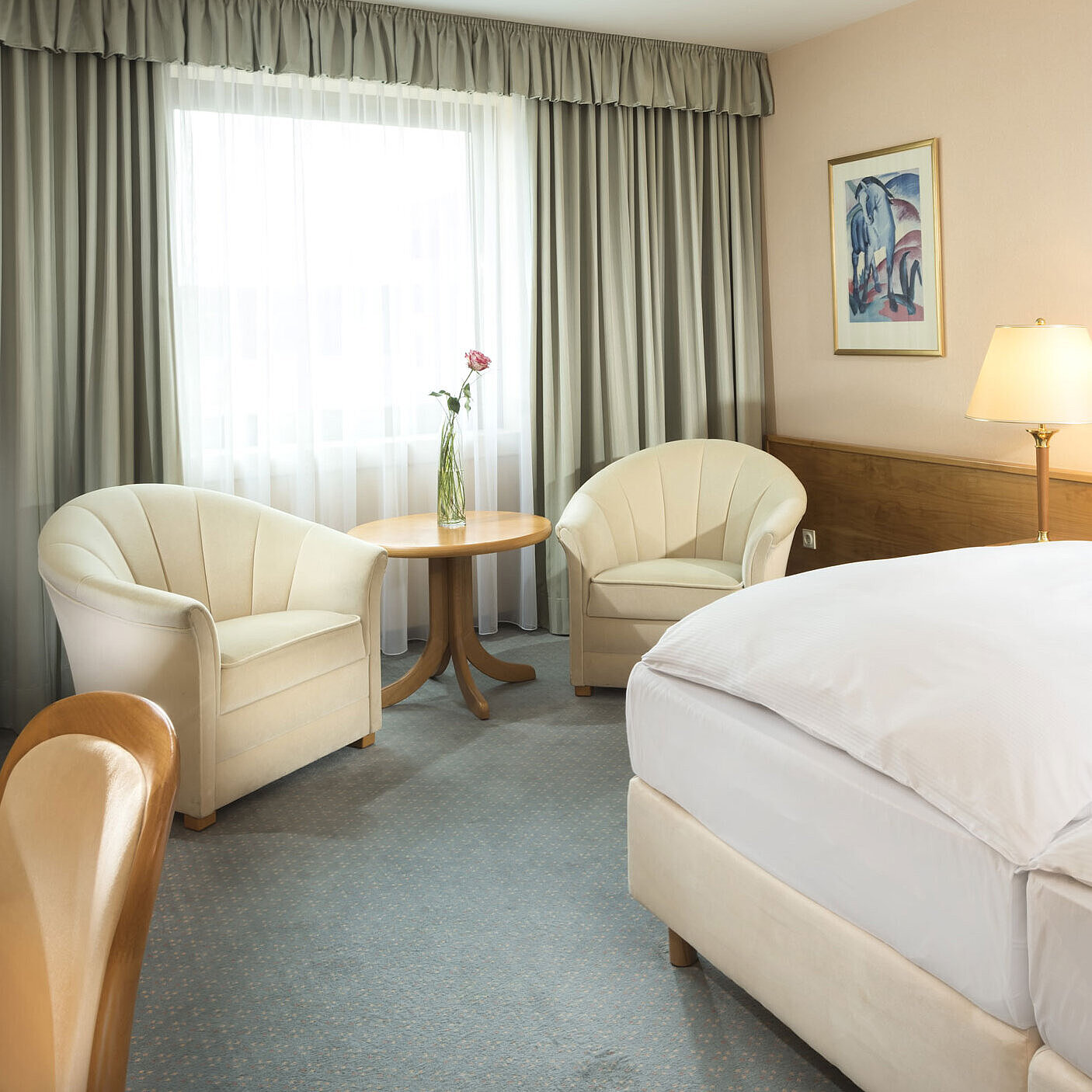Helles Hotelzimmer mit zwei Betten, Sitzgruppe und großem Fenster im Maritim Hotel Magdeburg