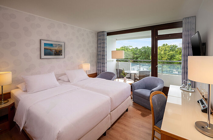 Classic Zimmer Classic Zimmer mit Doppelbett, Sitzecke, Schreibtisch und großem Fenster mit Blick ins Grüne