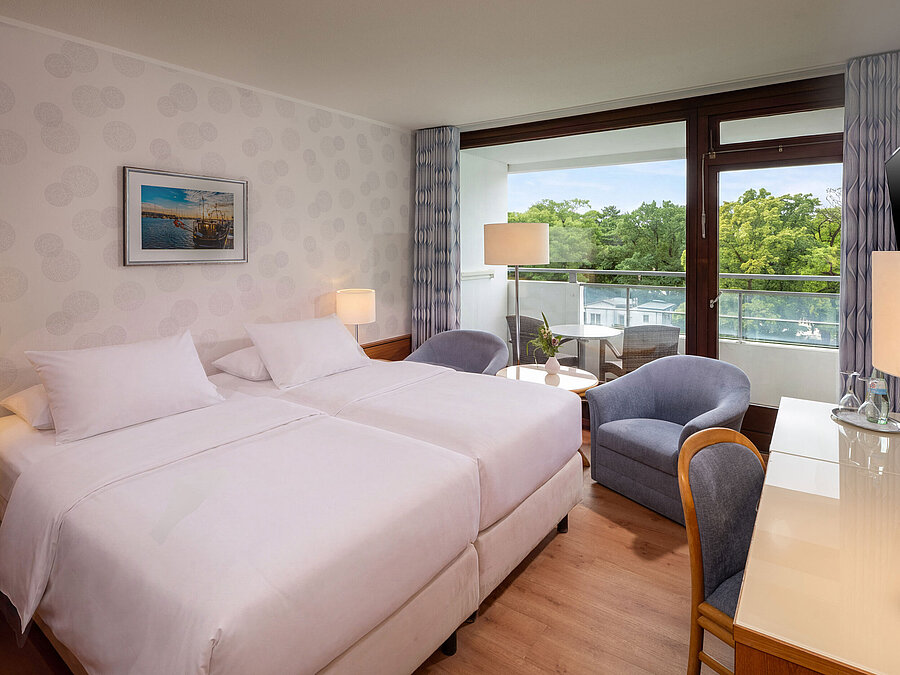 Classic Zimmer mit Doppelbett, Sitzecke, Schreibtisch und großem Fenster mit Blick ins Grüne
