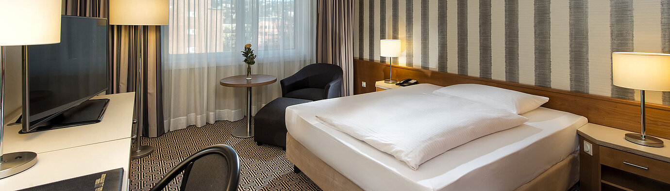 Modernes Einzelzimmer mit Schreibtisch, großem Fenster und Stadtblick im Maritim Hotel Stuttgart