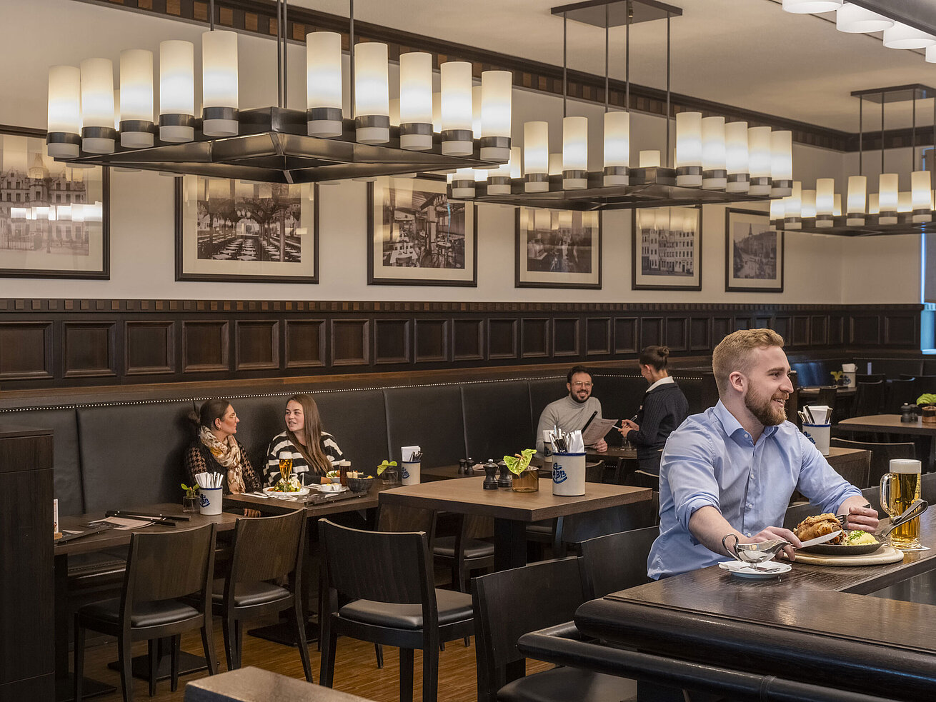 Gäste genießen Speisen im gemütlichen Restaurant "Rheinische Stov" des Maritim Hotel Düsseldorf mit stilvollem Interieur.