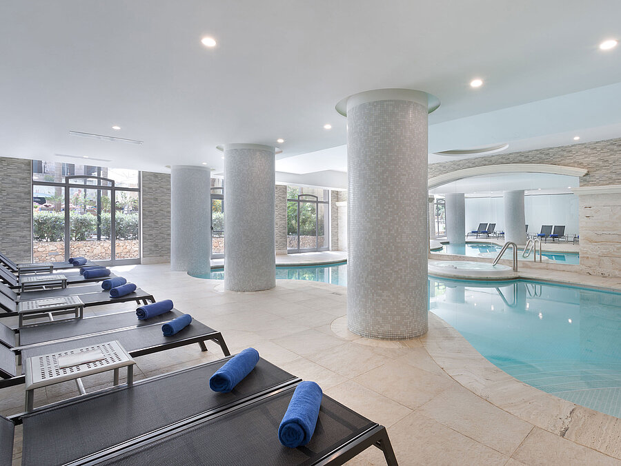 Moderner Innenpool mit Ruheliegen und Handtüchern im Spa des Maritim Antonine Hotel & Spa Malta für entspannende Wellnessmomente.