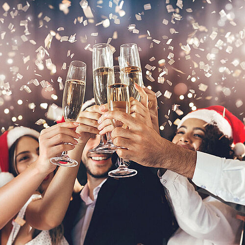 © Prostock-studio - AdobeStock.com Menschen stoßen bei einer festlichen Weihnachtsfeier mit Sekt an – fröhliche Stimmung in weihnachtlichem Ambiente
