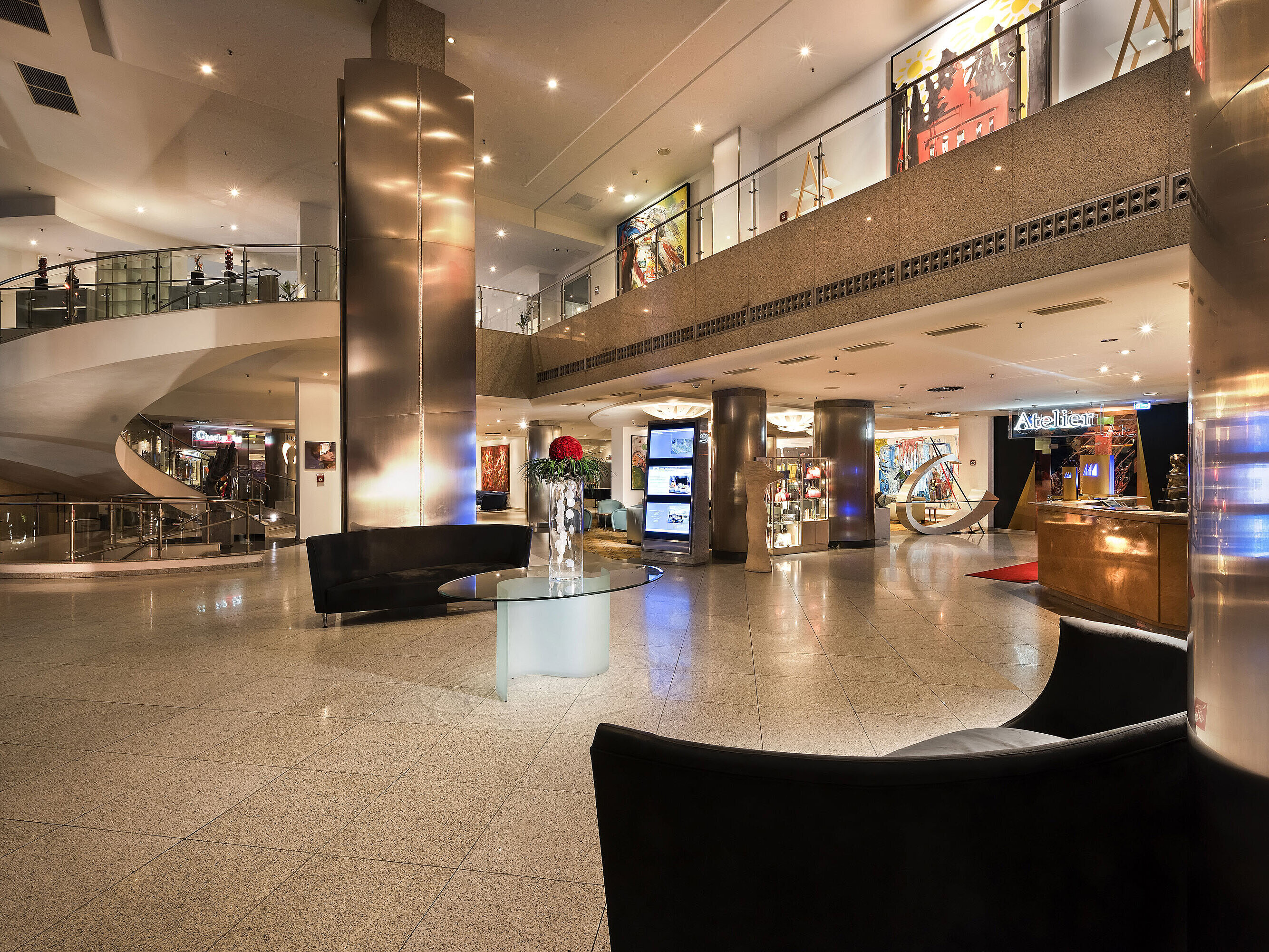 Stilvolle Lobby mit moderner Kunst und geschwungener Treppe im Maritim proArte Hotel Berlin.