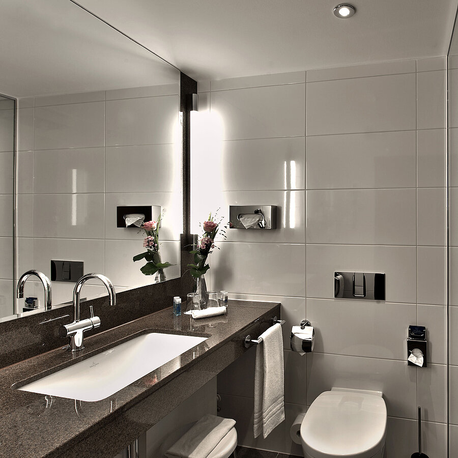 Modernes Badezimmer im Maritim Hotel Köln mit Badewanne, großer Spiegel und stilvoller Beleuchtung in neutralen Tönen.