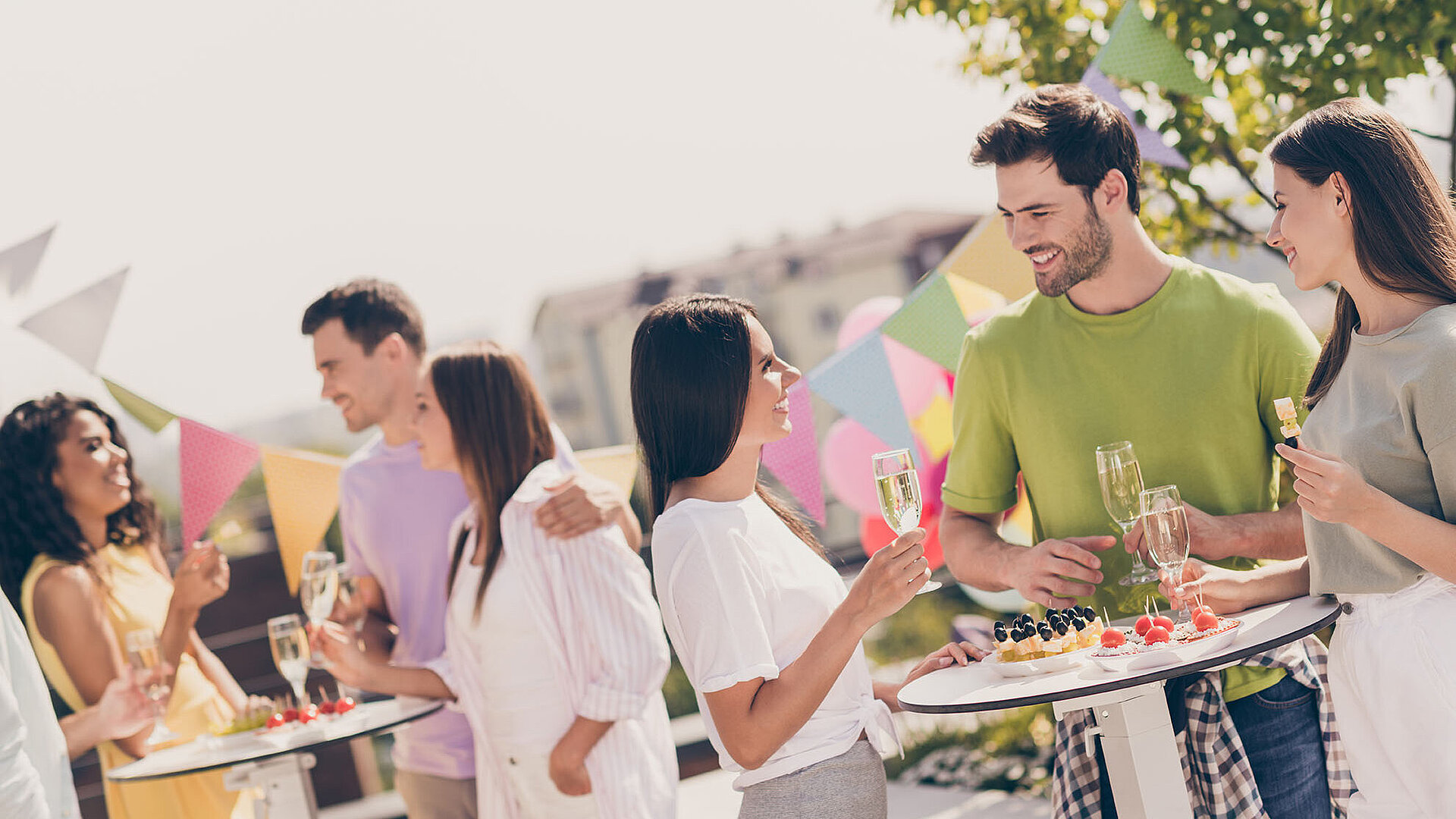 © deagreez / Adobestock.com Menschen unterhalten sich fröhlich bei einer Gartenparty mit Snacks und Sekt