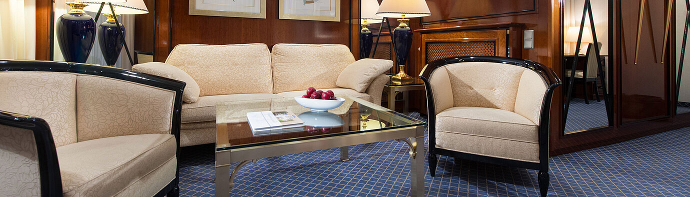 Eleganter Wohnbereich einer Suite im Maritim Hotel Fulda mit stilvollen Möbeln, Glas-Couchtisch und gemütlicher Beleuchtung.