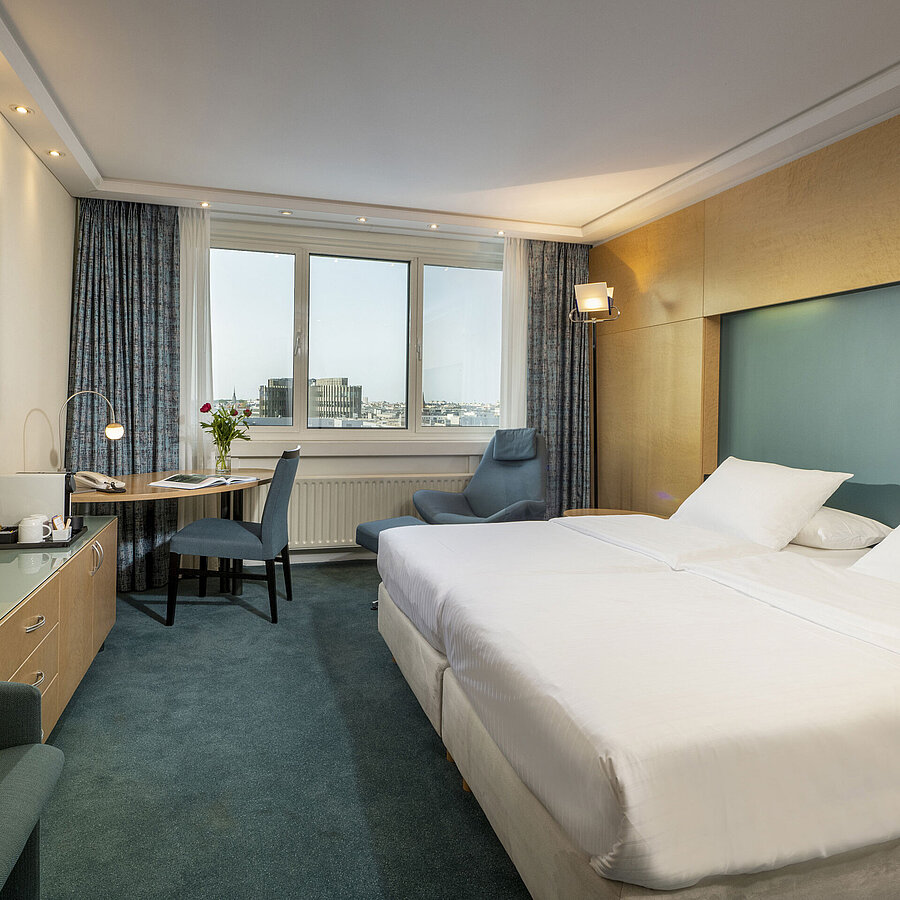 Modern eingerichtetes Superior-Zimmer im Maritim proArte mit großem Bett, Schreibtisch, Kunstwerk und Blick auf die Stadt.