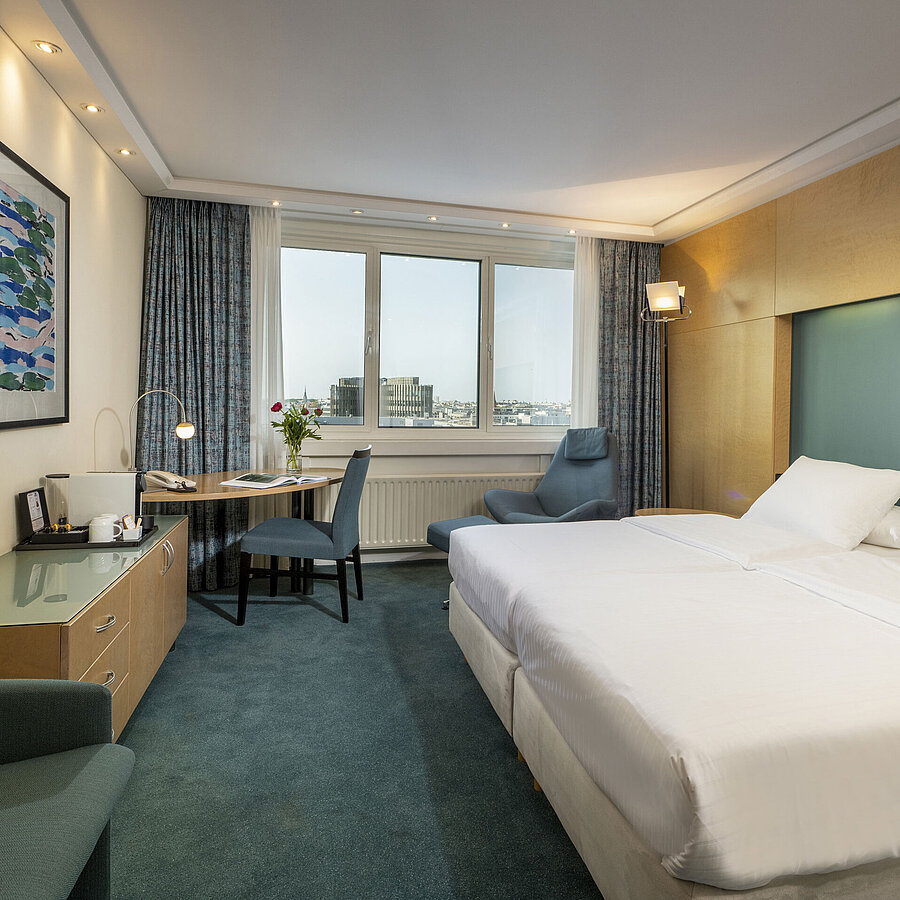 Modern eingerichtetes Superior-Zimmer im Maritim proArte mit großem Bett, Schreibtisch, Kunstwerk und Blick auf die Stadt.