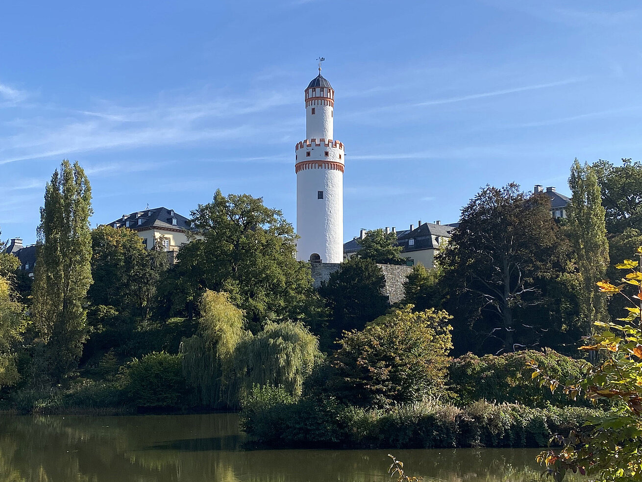Bad Homburg Schloss Weißer Turm in Bad Homburg vor blauem Himmel und umgeben von grüner Natur.