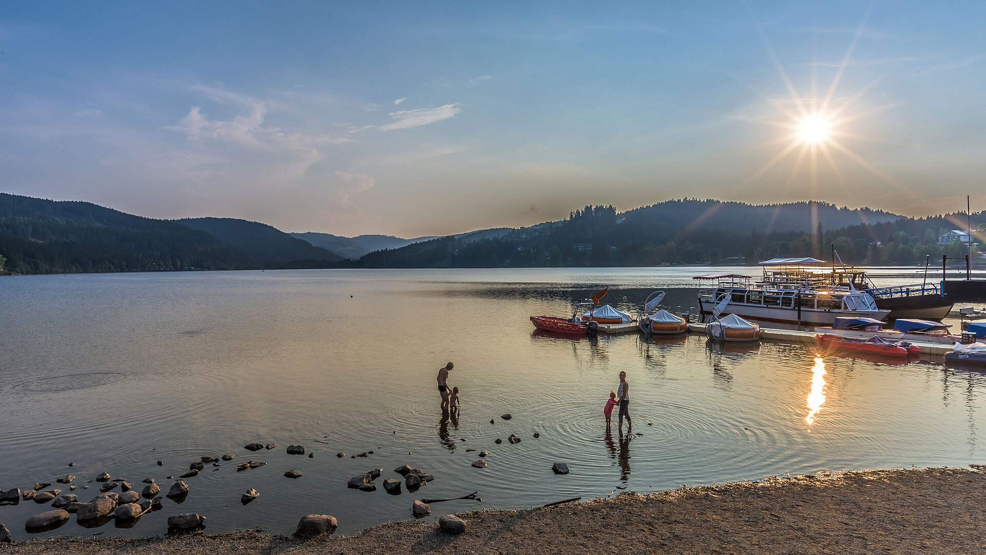 Sonnenuntergang am Titisee mit Badenden und Booten direkt am Maritim Hotel Titisee.