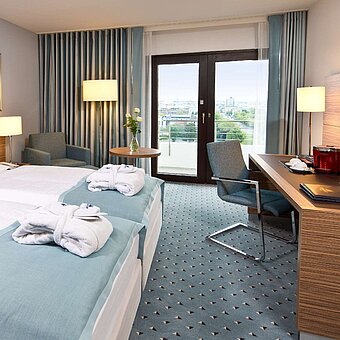 Superior Zimmer im Maritim Hotel Darmstadt mit stilvollem Design, Schreibtisch, Sitzecke und Doppelbett mit Bademänteln.