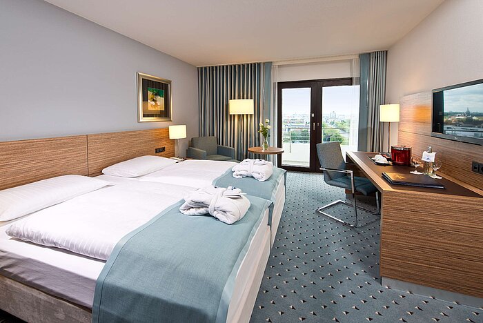 Superior Zimmer im Maritim Hotel Darmstadt mit stilvollem Design, Schreibtisch, Sitzecke und Doppelbett mit Bademänteln.