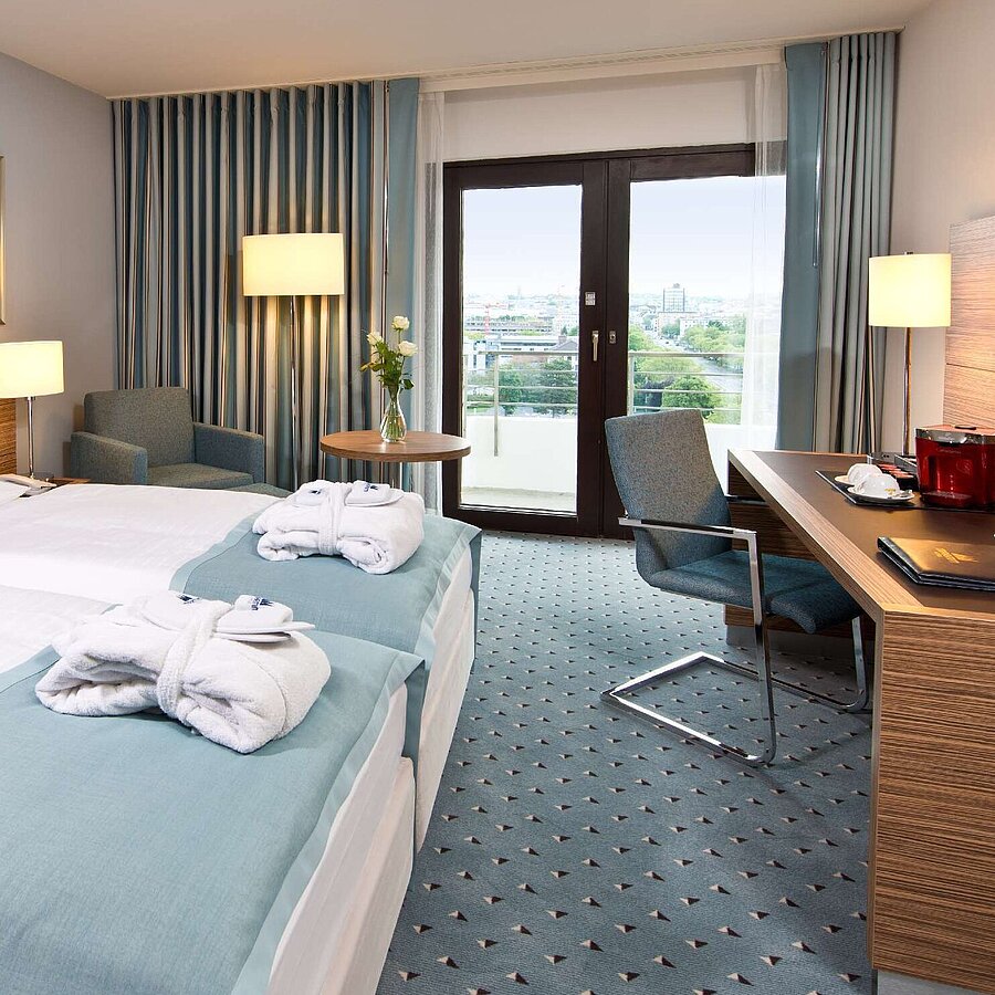 Superior Zimmer im Maritim Hotel Darmstadt mit stilvollem Design, Schreibtisch, Sitzecke und Doppelbett mit Bademänteln.