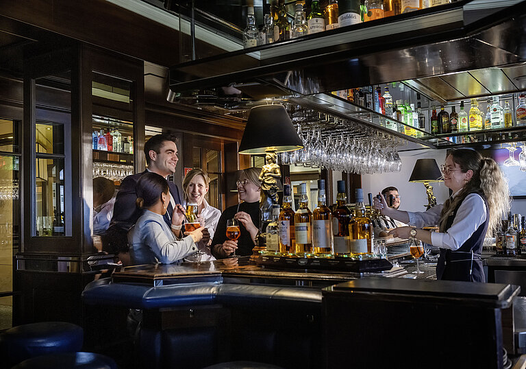 Gäste genießen Cocktails und gute Stimmung in der Bar des Maritim Hotels Darmstadt. Freundliches Barpersonal serviert Drinks.