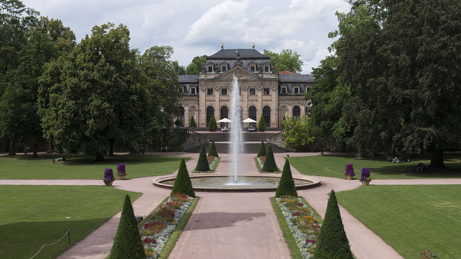 Die barocke Orangerie Fulda mit Schlossgarten, Springbrunnen und gepflegten Blumenbeeten im Vordergrund.