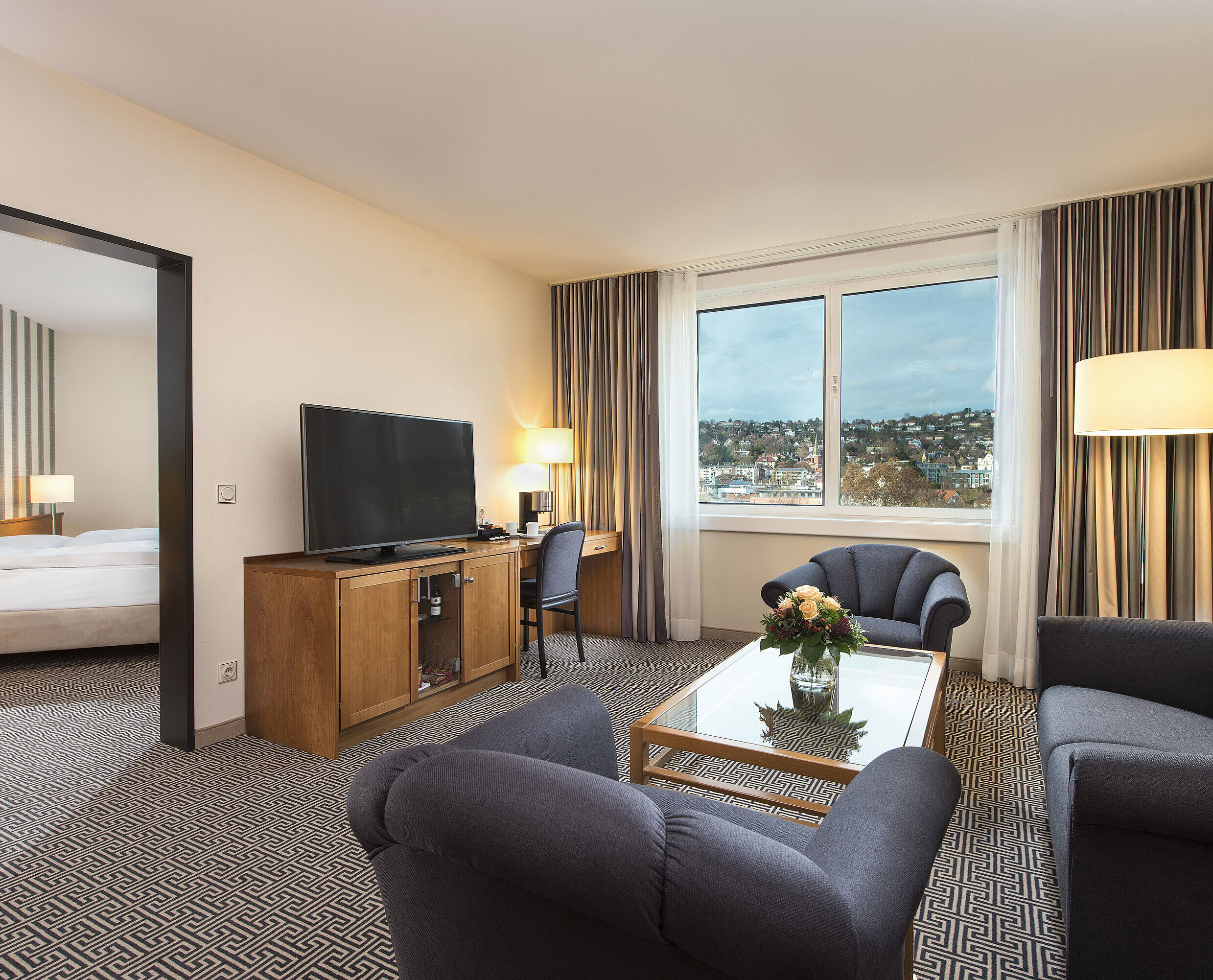 Junior Suite Helle Suite mit Stadtblick, Sofas, TV, Schreibtisch und Schlafzimmer im Maritim Hotel Stuttgart