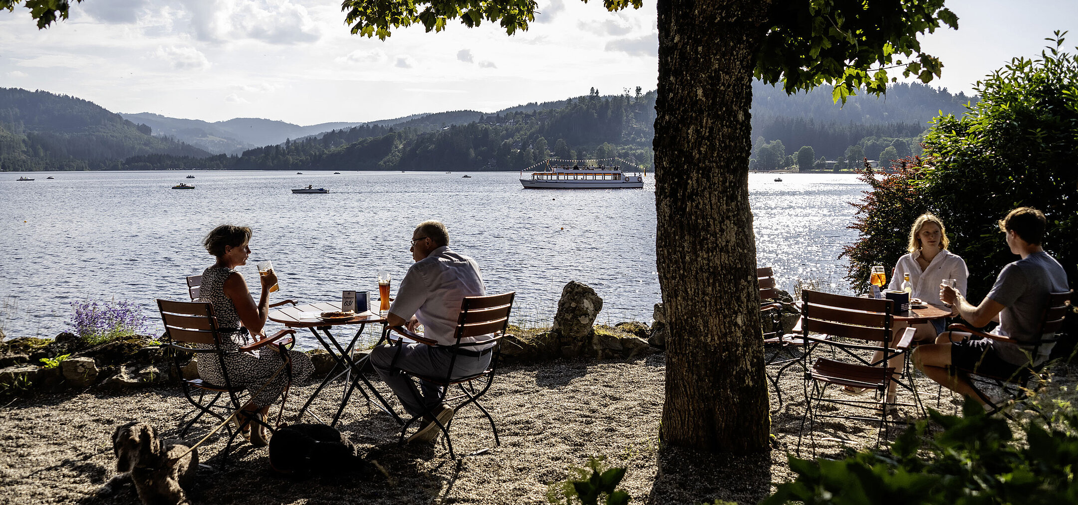Gäste entspannen im Biergarten des Maritim Hotel Titisee mit Blick auf den See und die Berge