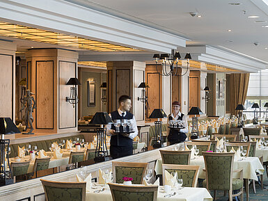 Restaurant 'Wintergarten' im Maritim Hotel Dresden mit gedeckten Tischen und freundlichem Servicepersonal.
