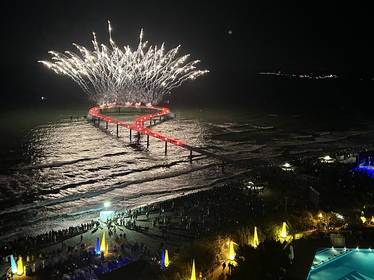 Spektakuläres Feuerwerk über der Seebrücke am Maritim Seehotel Timmendorfer Strand bei Nacht mit Pool und feiernden Gästen.