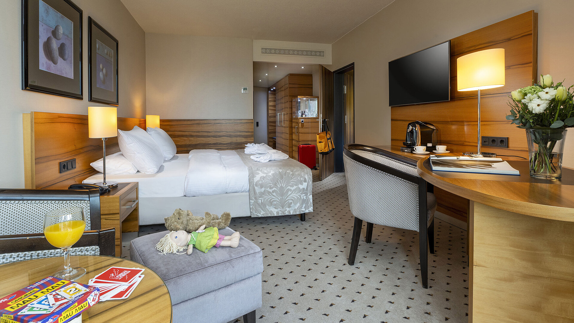 Komfortzimmer im Maritim Hotel Bad Homburg mit Doppelbett, Spielzeug, Kuscheltier und modernem Holzdekor.