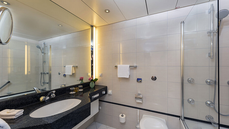 Modernes Badezimmer im Maritim Hotel Frankfurt mit großer Spiegelwand, stilvollem Waschbecken und Dusch-Badewanne.