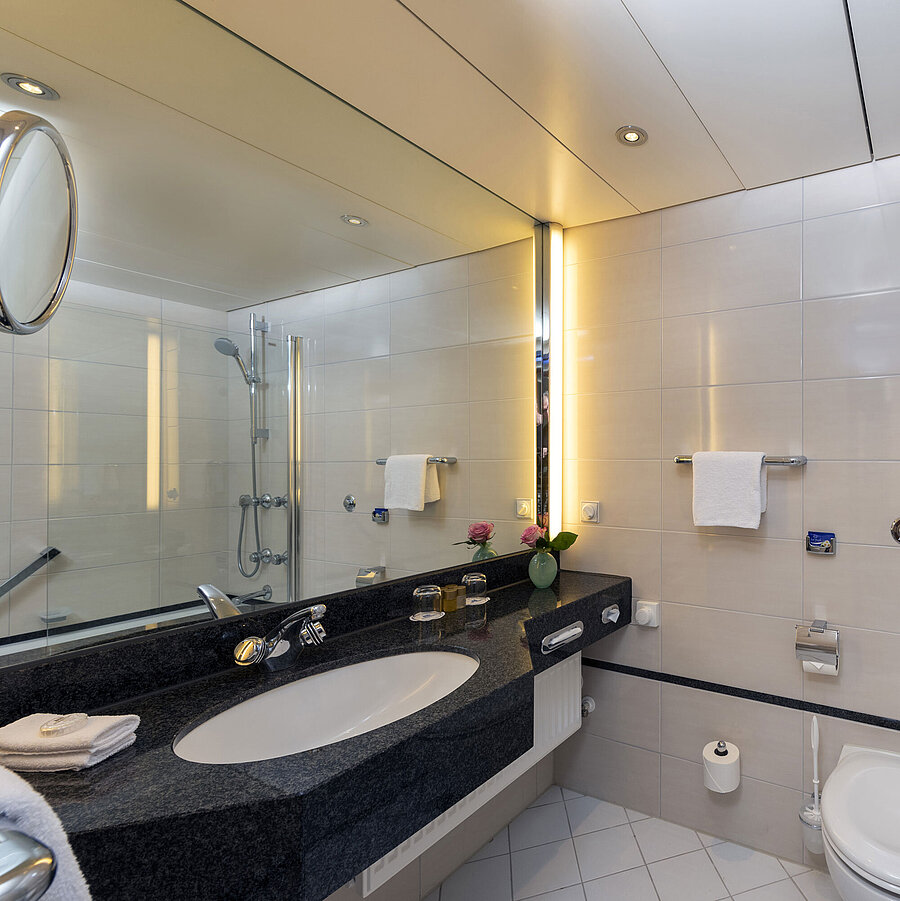 Modernes Badezimmer im Maritim Hotel Frankfurt mit großer Spiegelwand, stilvollem Waschbecken und Dusch-Badewanne.