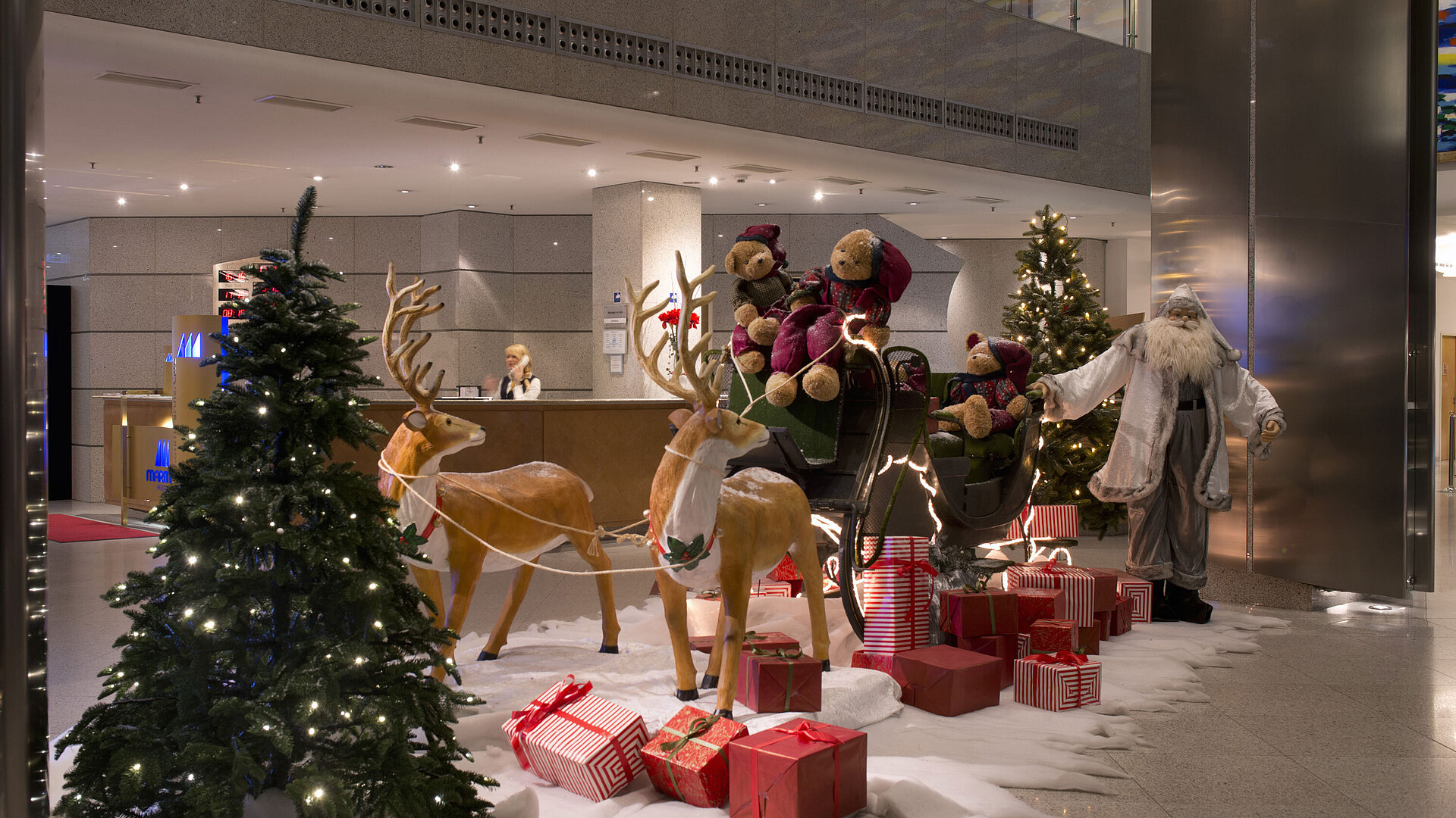 Festliche Dekoration in der Lobby des Maritim proArte Hotel Berlin mit Weihnachtsmann, Rentieren und Geschenken.