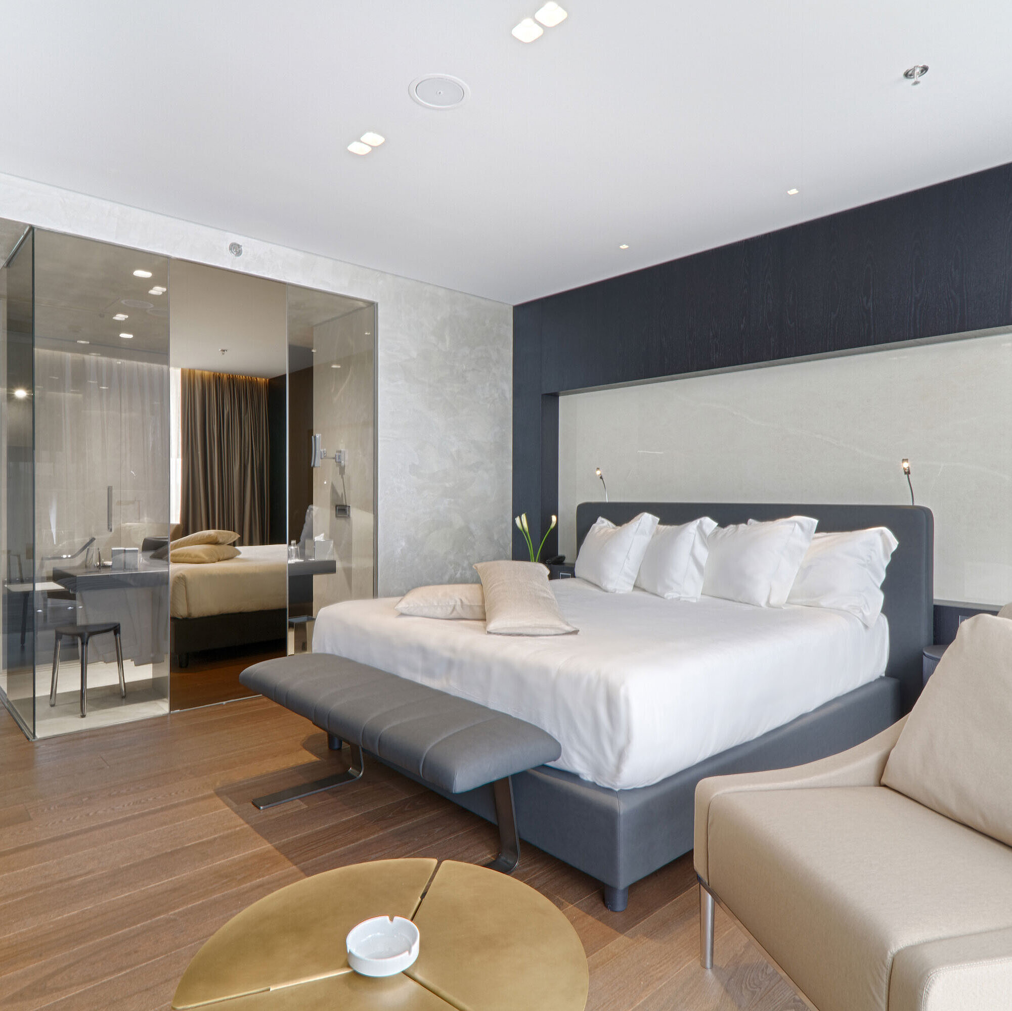 Großzügiges Doppelzimmer mit Sessel, Glastrennwand und modernem Design im Maritim Hotel Plaza Tirana