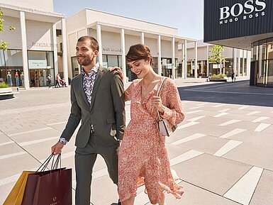 Shopping im Outlet Center Paar beim Shopping in modernem Outlet Center mit Einkaufstüten und Markenstores