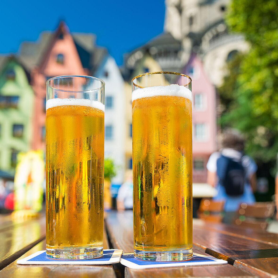 Zwei Gläser Bier auf Tisch im Biergarten vor historischer Altstadt