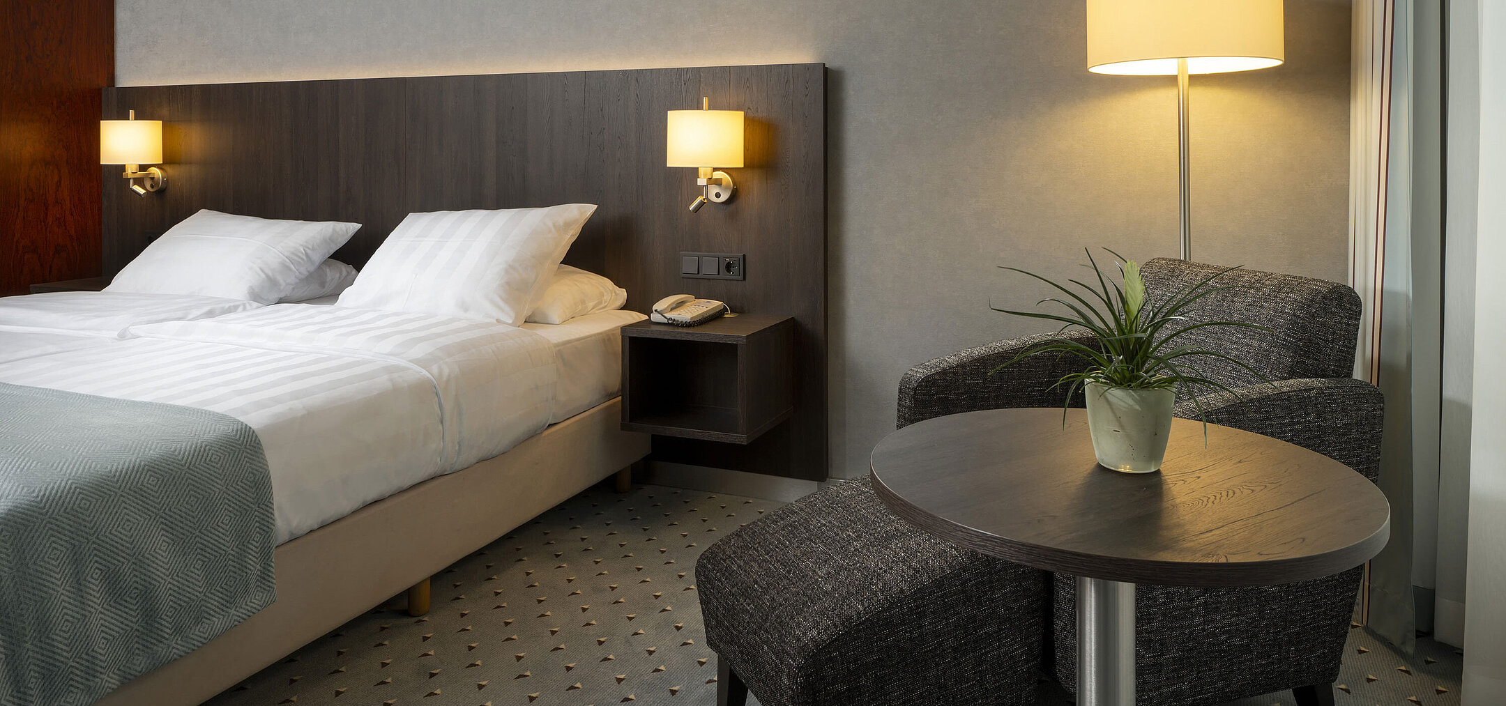 Komfortables Einzelzimmer im Maritim Hotel Bremen mit gemütlicher Sitzecke, eleganter Beleuchtung und modernem Doppelbett.