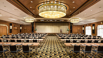 Eleganter Tagungssaal mit Bühne, Kronleuchtern und moderner Bestuhlung im Maritim Hotel Königswinter.