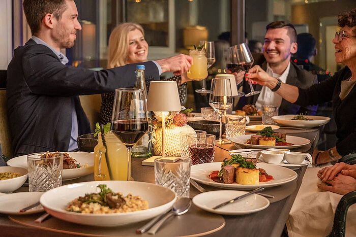Gäste genießen ein gemeinsames Dinner im Restaurant an einem stilvoll gedeckten Tisch