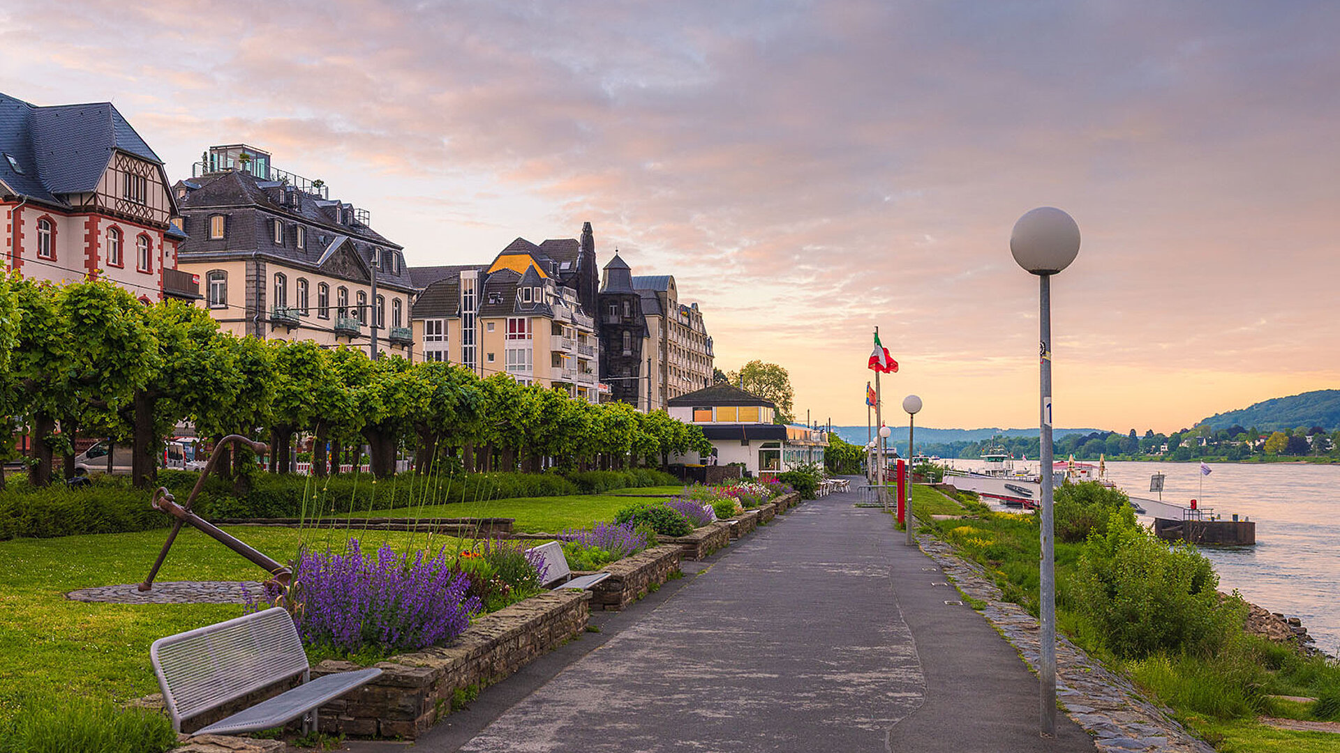 © lic0001 - Adobestock.com Rheinpromenade in Königswinter mit Blumenbeeten, Spazierweg und Blick auf den Rhein bei Abendstimmung.