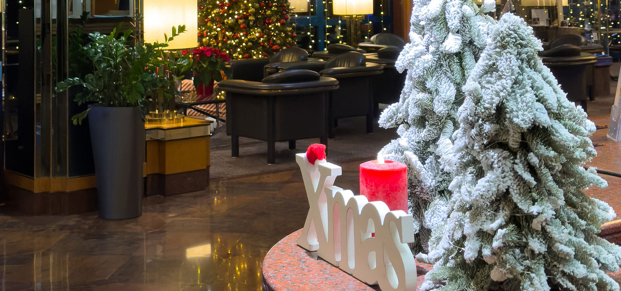 Weihnachtlich geschmückte Hotellobby Festlich dekorierte Hotellobby mit geschmückten Weihnachtsbäumen, Kronleuchter und winterlicher Atmosphäre.