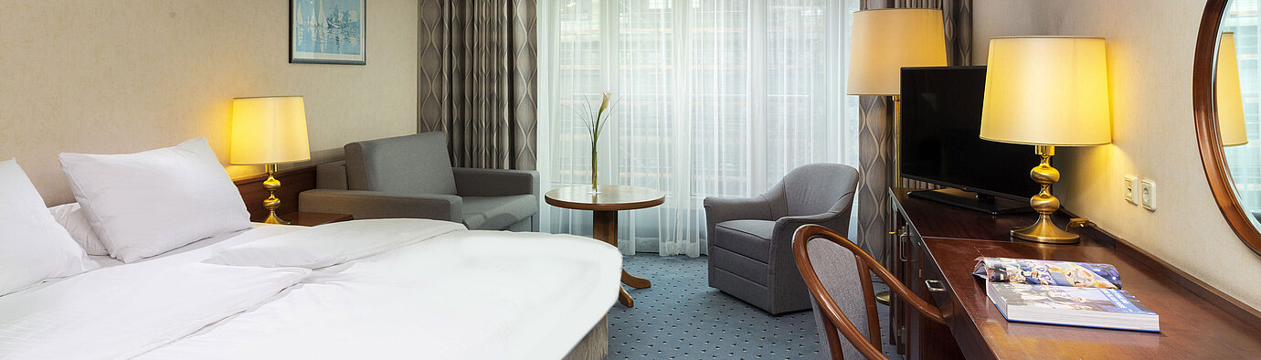 Helles Familienzimmer im Maritim Hotel Köln mit Doppelbett, Schreibtisch, Fernseher,Sesseln und großen Fenstern mit Vorhängen
