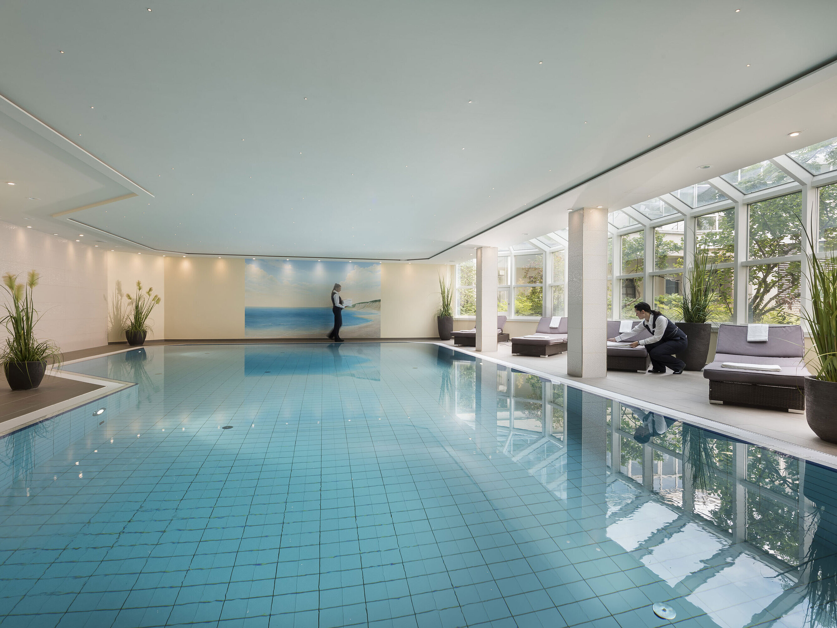 Großer Innenpool im Maritim Hotel Würzburg mit Glasfront, Liegen und freundlichem Service.