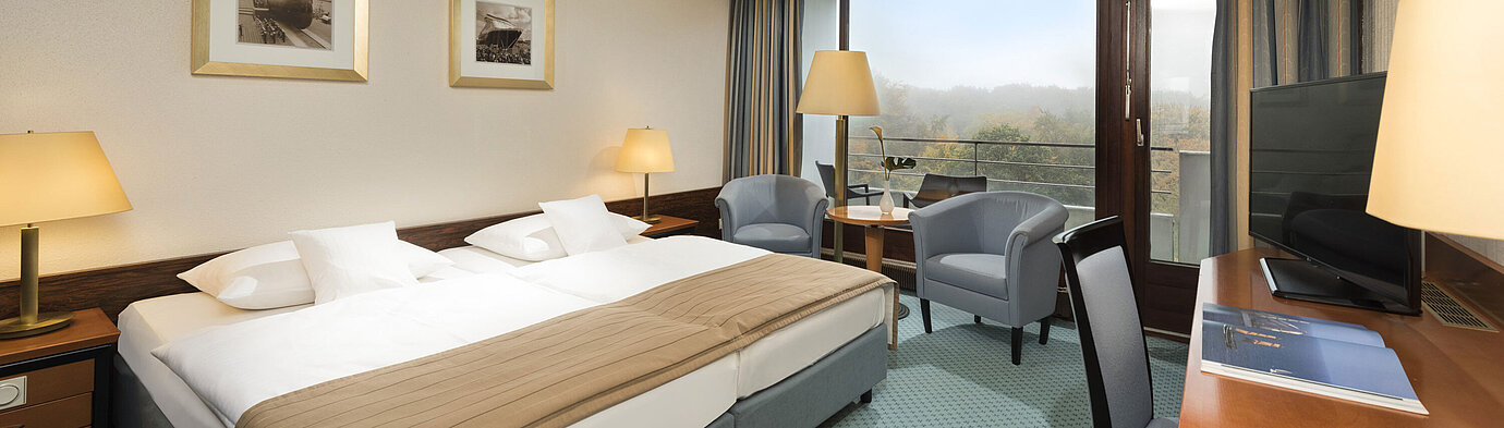 Classic Zimmer  Classic Zimmer im Maritim Hotel Kiel mit großem Doppelbett, Sitzbereich, Schreibtisch und Balkon mit Blick ins Grüne.