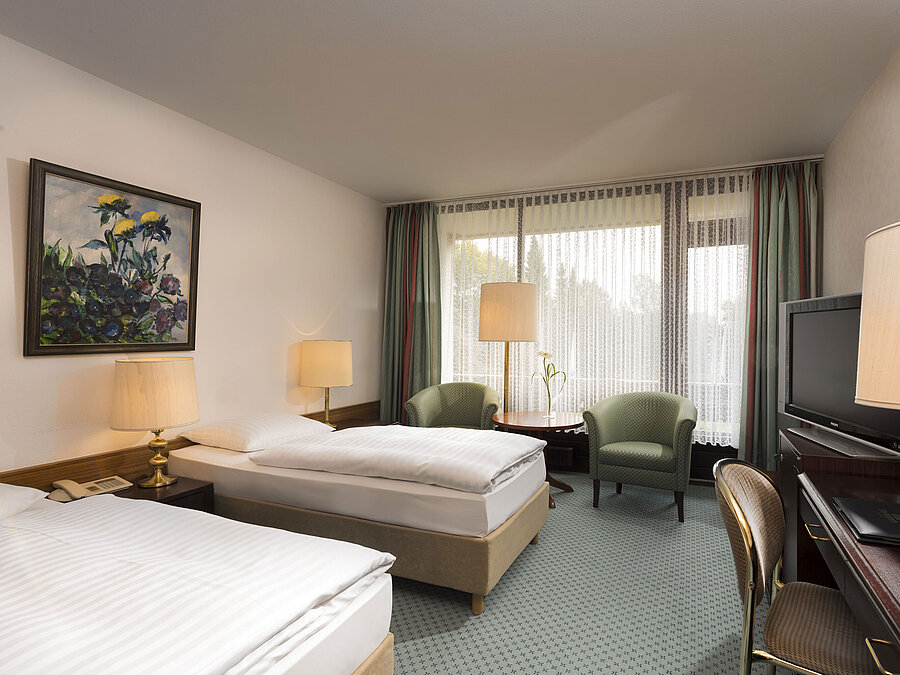 Doppelzimmer mit zwei Betten, Sesseln, Schreibtisch und Balkon im Maritim Hotel Bad Salzuflen