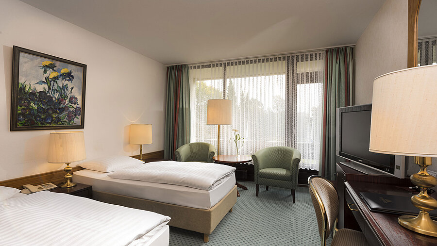 Doppelzimmer mit zwei Betten, Sesseln, Schreibtisch und Balkon im Maritim Hotel Bad Salzuflen