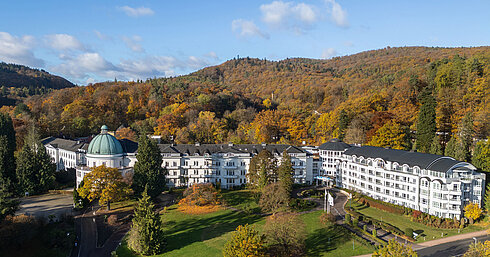 Außenansicht des Maritim Hotel Bad Wildungen, umgeben von Park, Bäumen und herbstlichem Waldpanorama.