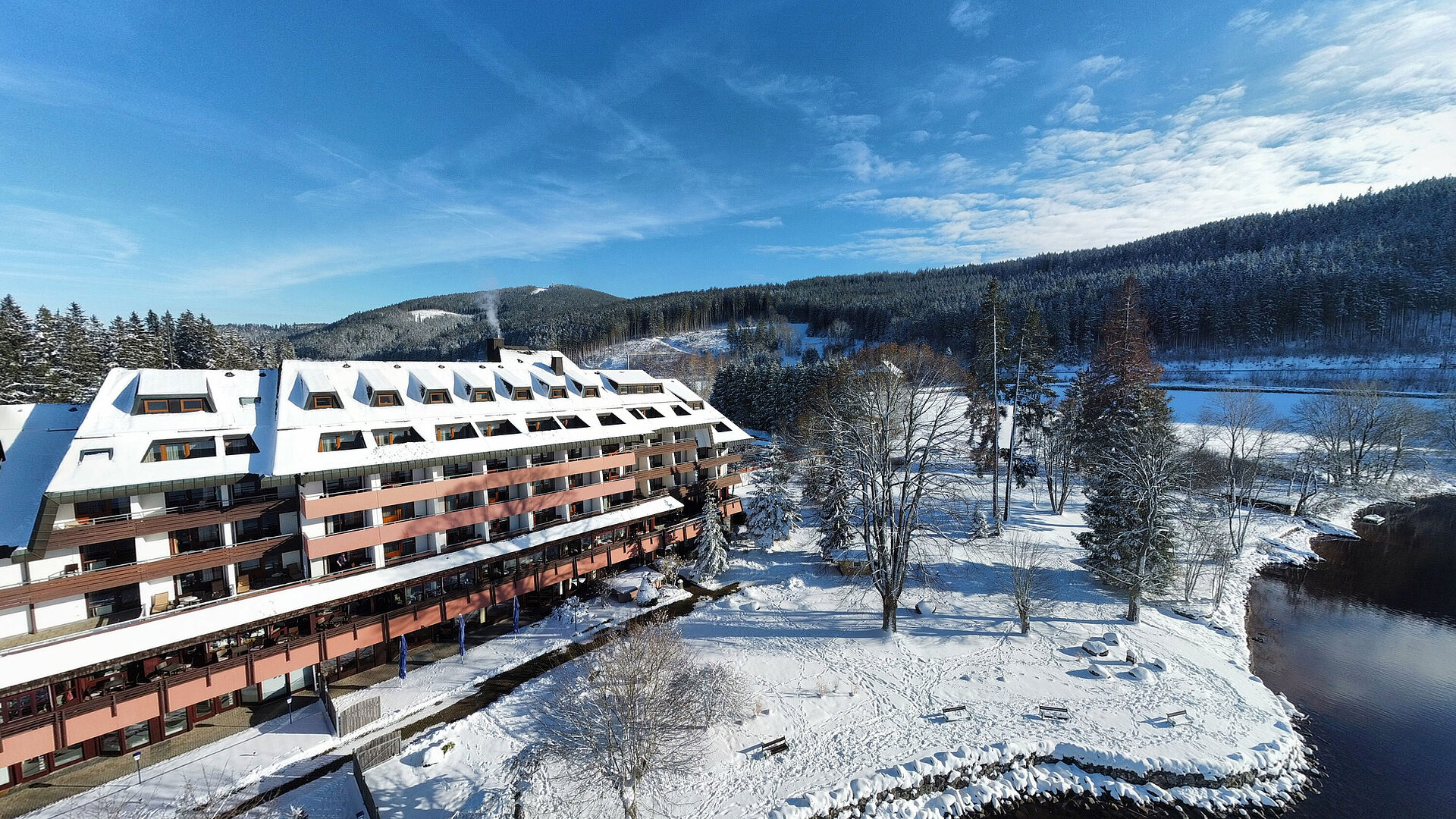 Außenansicht Maritim Hotel Titisee im Winter mit verschneitem Garten und Blick auf das Hotelgebäude am Ufer