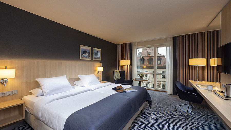 Elegantes Superior Zimmer im Maritim Hotel Würzburg mit großem Doppelbett und Ausblick auf historische Dächer
