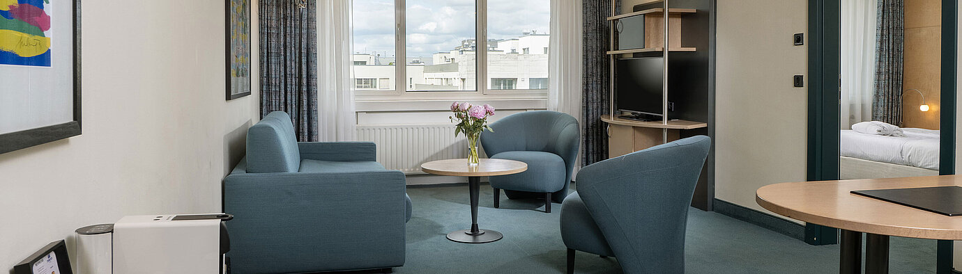 Helle Suite mit Sitzgruppe, großem Fenster und Kaffeemaschine im Maritim proArte Hotel Berlin